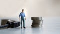 Business concept about work and wages. MiniatureÃÂ manÃÂ standingÃÂ betweenÃÂ aÃÂ cableÃÂ lineÃÂ andÃÂ aÃÂ pileÃÂ ofÃÂ coin.